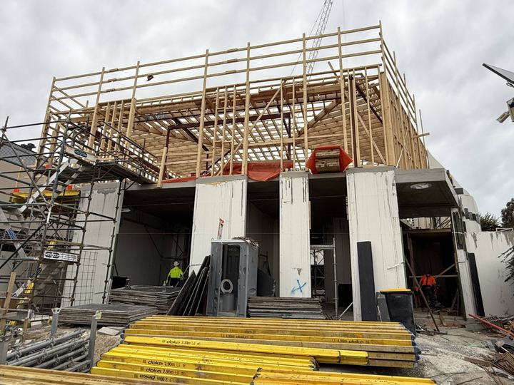 A timber frame going up on a two-storey home, with scaffolding.
